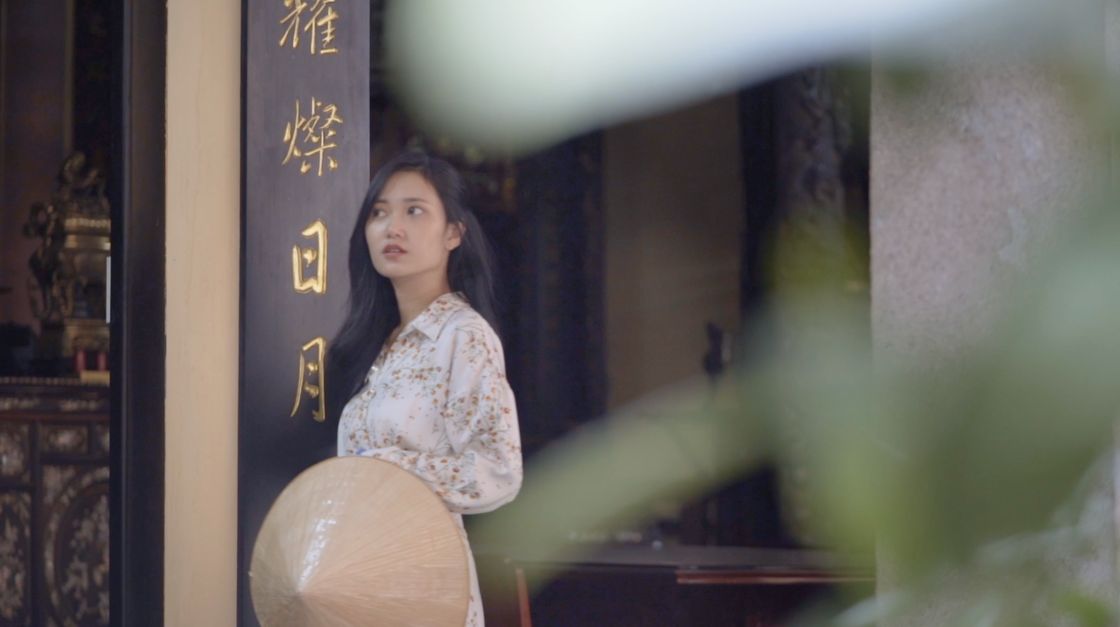 A woman in áo dài at a temple doorway